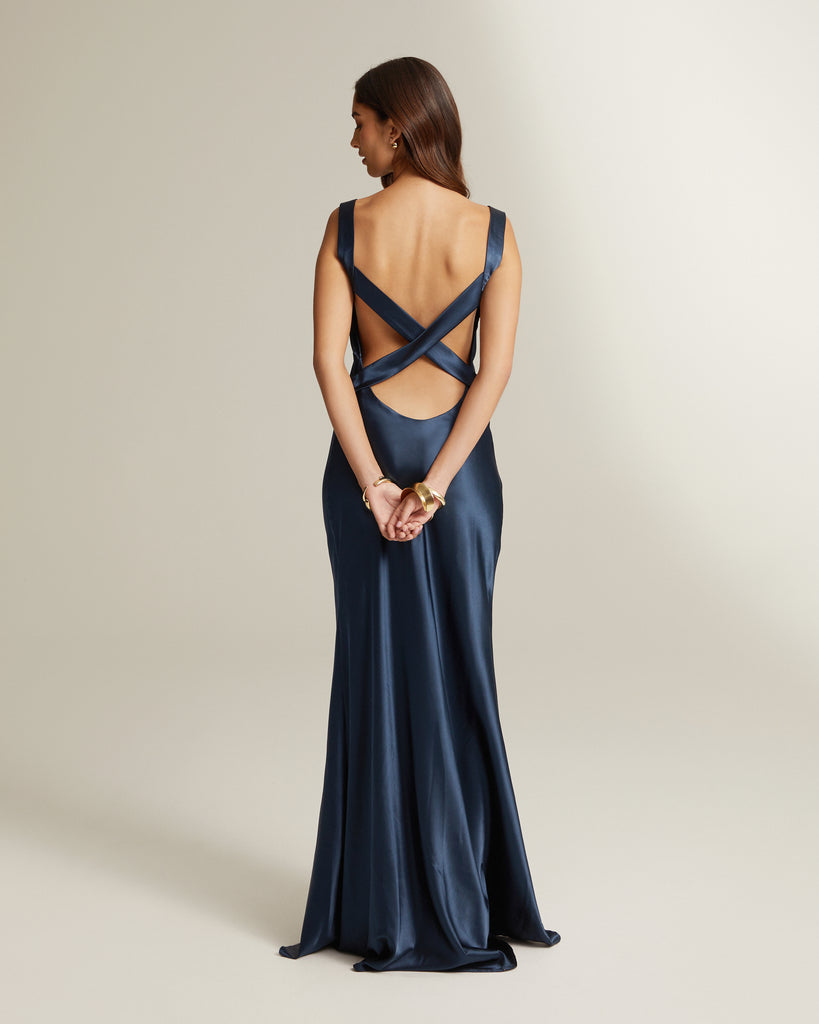 A back view of a navy blue, full length dress with a v-neckline and no sleeves